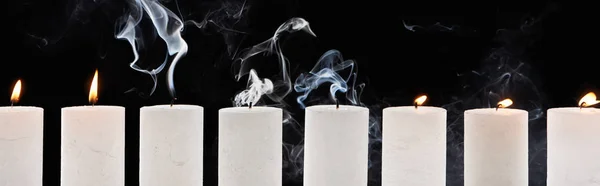 Burning and extinct white candles with smoke on black background, panoramic shot — Stock Photo