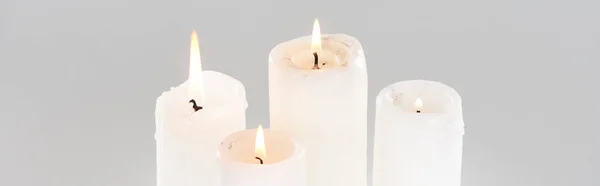 Weiße brennende Kerzen, die isoliert auf grauen, panoramischen Aufnahmen glühen — Stockfoto