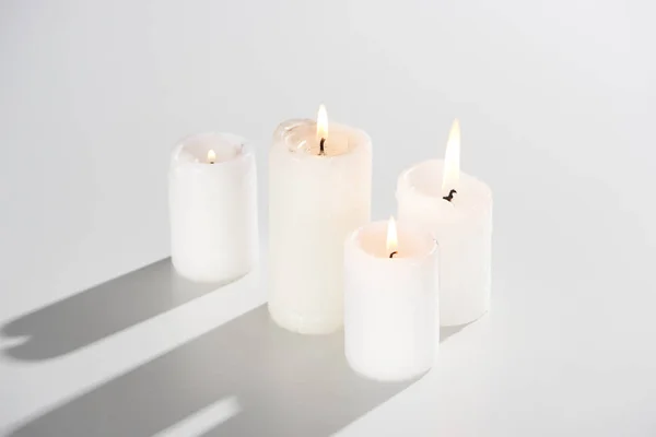 Горящие свечи, светящиеся на белом фоне с тенью — стоковое фото