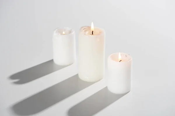 Queimando velas brilhando no fundo branco com sombra — Fotografia de Stock