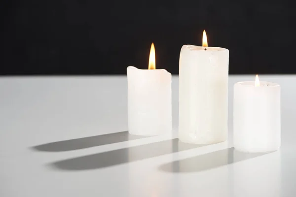 Queimando velas brancas na superfície branca brilhando isolado no preto — Fotografia de Stock