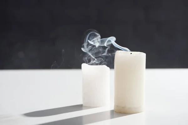 Extinct white candles with smoke on black background — Stock Photo