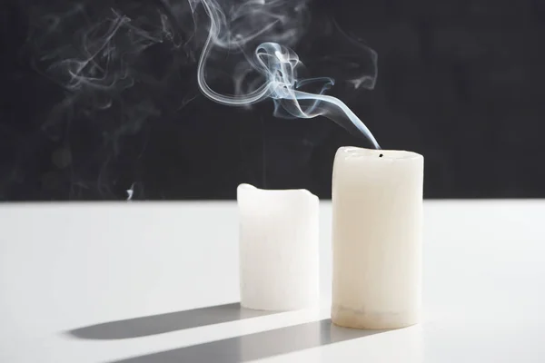 Extinct white candles with smoke on black background — Stock Photo