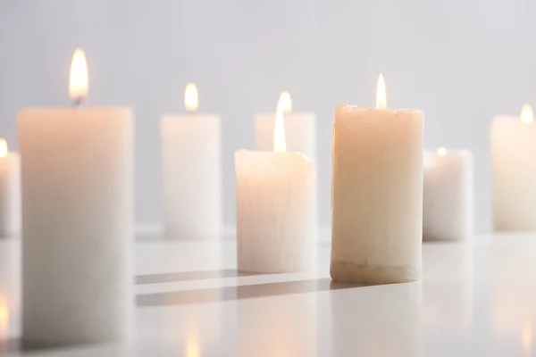 Foco seletivo da queima de velas brancas na superfície branca brilhando isolado no cinza — Fotografia de Stock