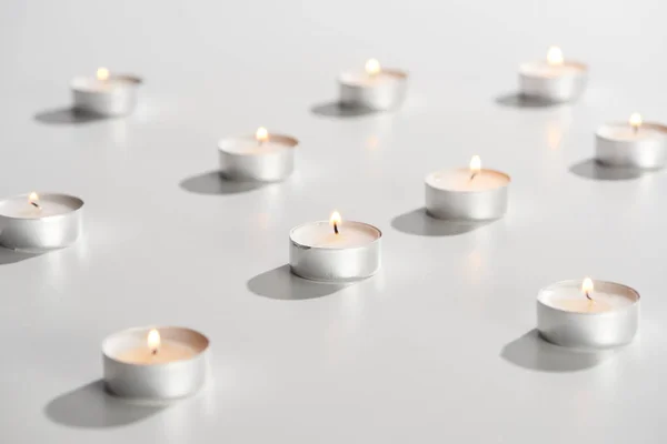 Selective focus of burning candles glowing on white surface — Stock Photo