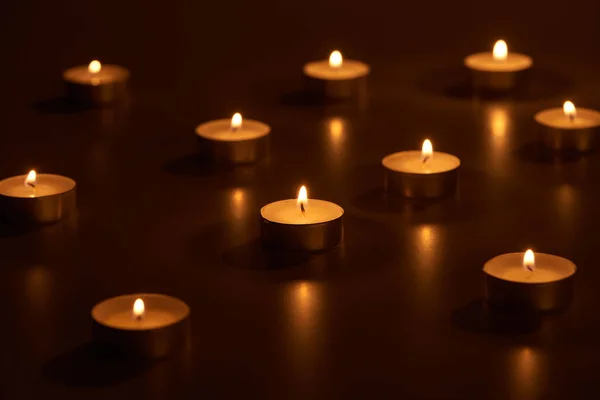 Selective focus of burning white candles glowing in dark — Stock Photo