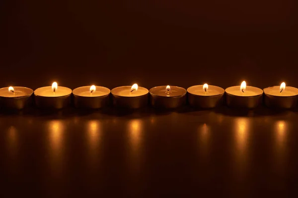 Burning white candles glowing in dark — Stock Photo