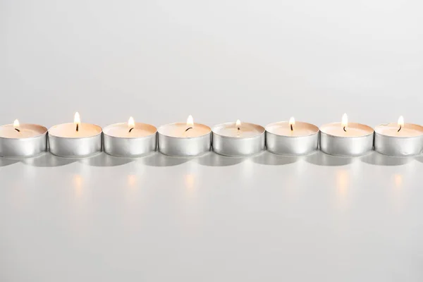 Queimando velas brilhando em linha no fundo branco — Fotografia de Stock