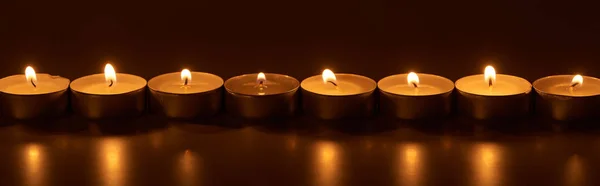 Burning white candles glowing in dark, panoramic shot — Stock Photo