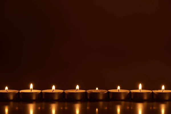 Burning white candles glowing in dark — Stock Photo