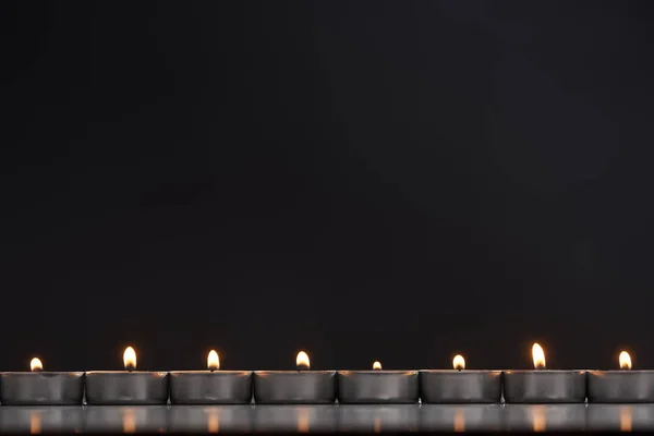 Палаючі свічки, розташовані в лінії, що світиться ізольовані на чорному — стокове фото