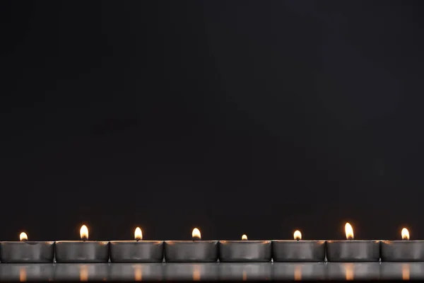 Burning candles arranged in line glowing isolated on black — Stock Photo