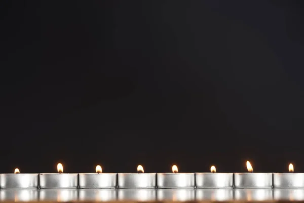 Queimando velas dispostas em linha brilhando isolado em preto — Fotografia de Stock