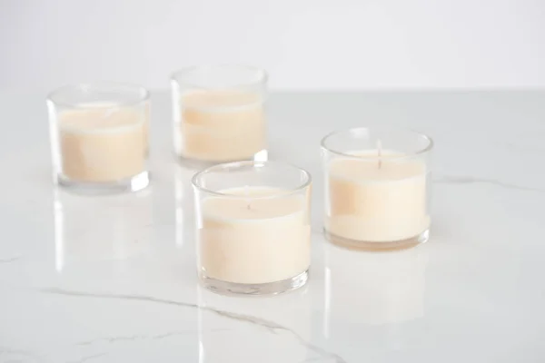 Messa a fuoco selettiva di candele bianche in vetro su superficie di marmo bianco — Foto stock