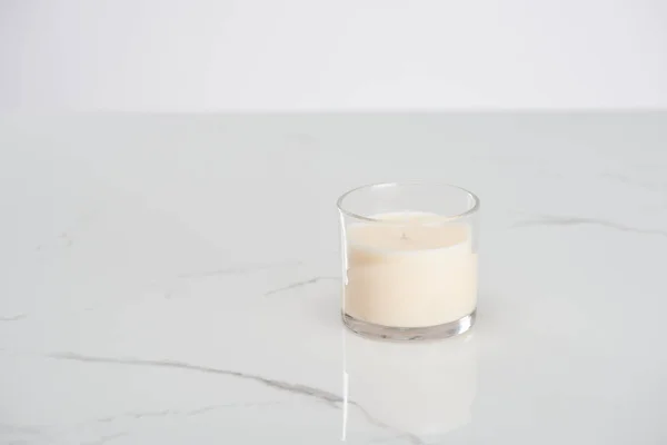 White candle in glass on marble white surface — Stock Photo