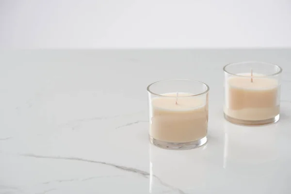 White candles in glass on marble white surface — Stock Photo