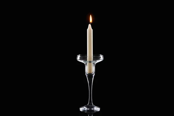 Burning white candle glowing in glass candlestick isolated on black — Stock Photo