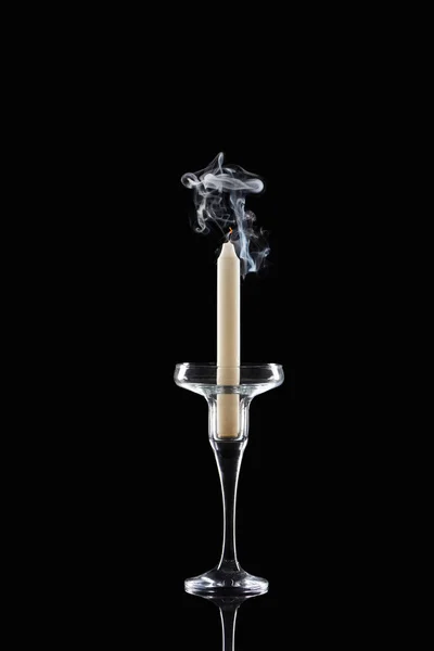 Extinct white candle in glass candlestick with smoke on black background — Stock Photo