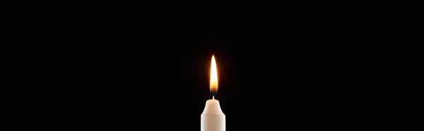 Burning white candle glowing isolated on black, panoramic shot — Stock Photo