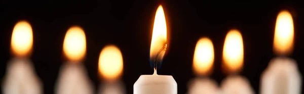 Selective focus of burning white candle glowing isolated on black, panoramic shot — Stock Photo