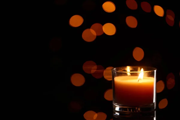 Burning candle glowing in dark with bokeh lights on background — Stock Photo