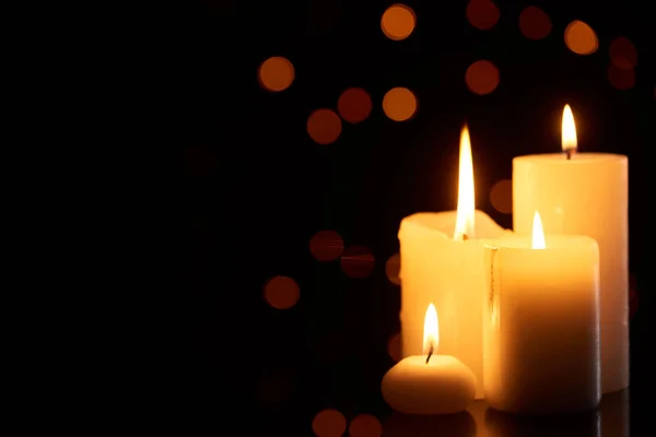 Burning candles glowing in dark with bokeh lights on background — Stock Photo