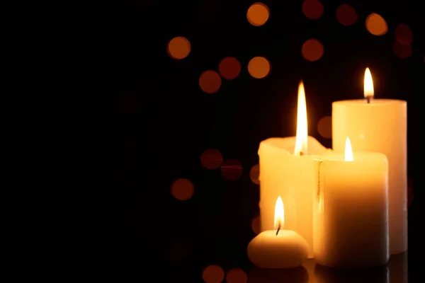 Burning candles glowing in dark with bokeh lights on background — Stock Photo