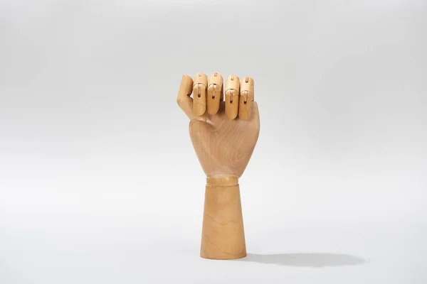 Hand of wooden doll in fist on grey background — Stock Photo