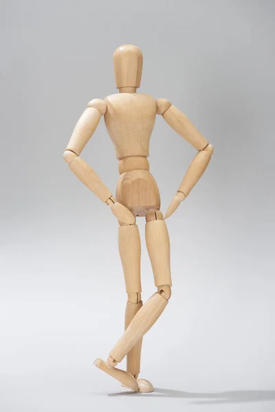 Bambola in legno con le mani sui fianchi su sfondo grigio — Foto stock