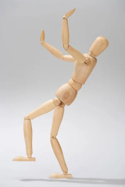 Деревянная кукла с поднятыми руками на сером фоне — стоковое фото