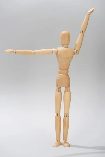 Wooden puppet with raised hands on grey background — Stock Photo