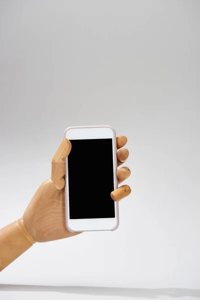 Hand of wooden doll with smartphone on grey background — Stock Photo