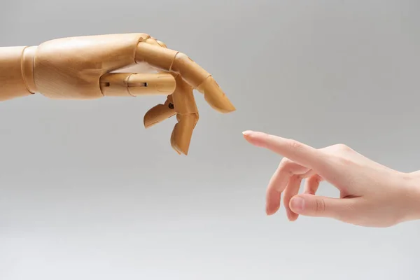 Abgeschnittene Ansicht einer Frau und der Hand einer hölzernen Puppe, die sich isoliert auf grau die Finger zuzieht — Stockfoto
