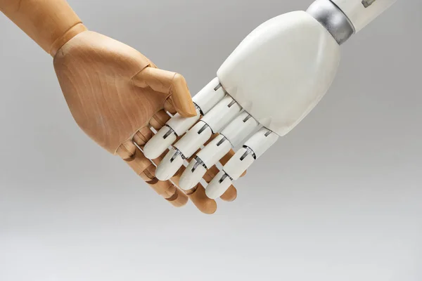 Wooden doll and robot handshaking isolated on grey — Stock Photo