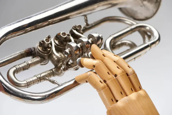 Close up view of wooden hand of doll with alto horn isolated on grey — Stock Photo