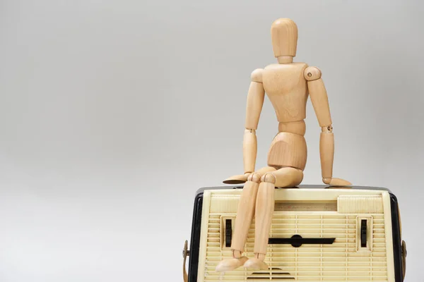 Wooden doll on vintage radio isolated on grey — Stock Photo