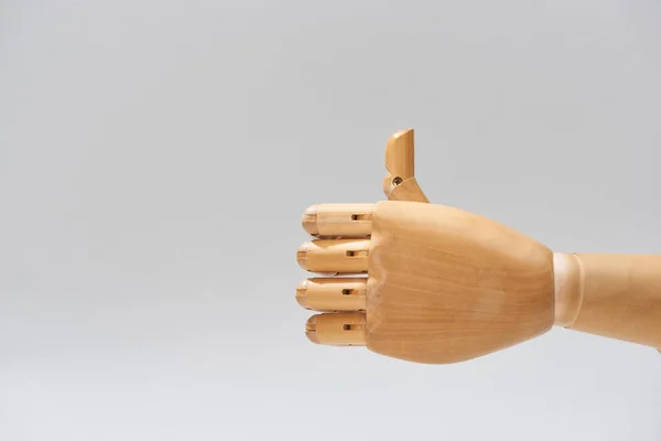 Main de poupée en bois avec le pouce vers le haut geste isolé sur gris — Photo de stock