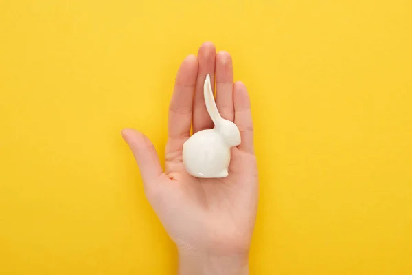 Cropped view of woman holding white Easter bunny on colorful yellow background — Stock Photo