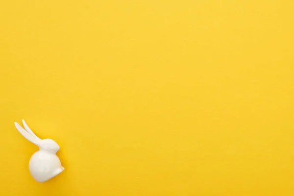 Вид зверху на білого великоднього кролика на барвистому жовтому тлі з копіювальним простором — стокове фото