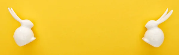 Draufsicht auf weiße Osterhasen auf farbenfrohem gelben Hintergrund, Panoramaaufnahme — Stockfoto