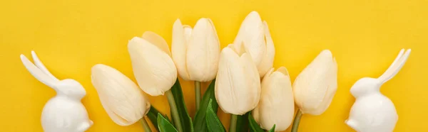 Draufsicht auf Tulpen und weiße Osterhasen auf farbenfrohem gelben Hintergrund, Panoramaaufnahme — Stockfoto