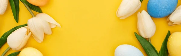 Vista superior de tulipas e ovos de Páscoa pintados sobre fundo amarelo colorido com espaço de cópia, tiro panorâmico — Fotografia de Stock
