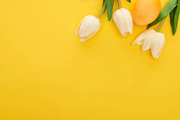 Draufsicht auf Tulpen und bemaltes Osterei auf buntem gelben Hintergrund — Stockfoto