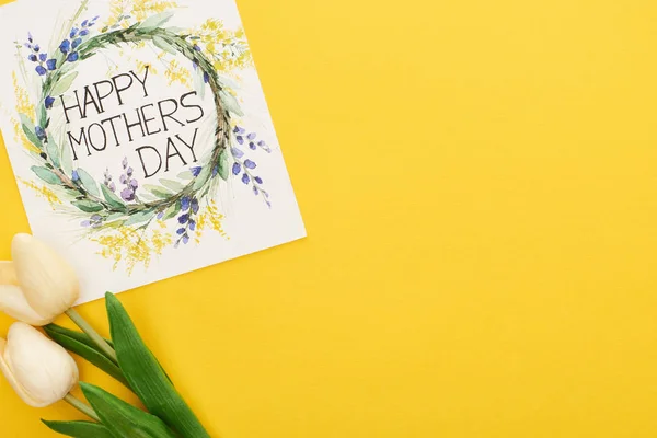 Вид зверху весняних тюльпанів і вітальна листівка з днем матері на барвистому жовтому фоні — стокове фото