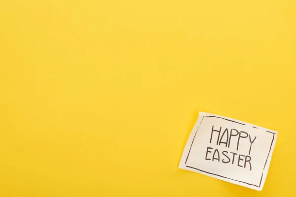 Vista superior de la tarjeta de felicitación con letras de Pascua feliz sobre fondo amarillo colorido - foto de stock