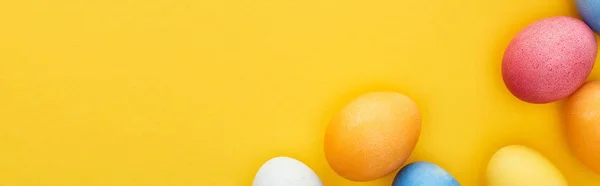 Top view of multicolored painted Easter eggs on yellow background with copy space, panoramic shot — Stock Photo