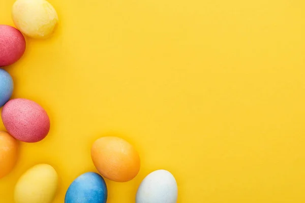 Draufsicht auf bunt bemalte Ostereier auf gelbem Hintergrund mit Kopierraum — Stockfoto