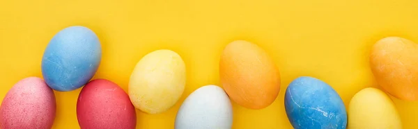 Vista superior de ovos de Páscoa pintados multicoloridos no fundo amarelo, tiro panorâmico — Fotografia de Stock