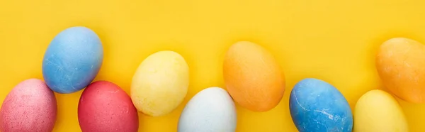 Top view of multicolored painted Easter eggs on yellow background, panoramic shot — Stock Photo