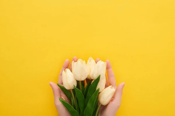 Vista cortada de mulher segurando tulipas primavera no fundo amarelo colorido — Fotografia de Stock